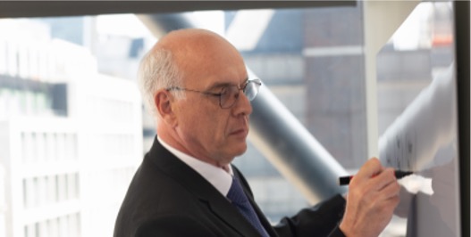 Professional consultant writing on a whiteboard during a workshop or planning session.
